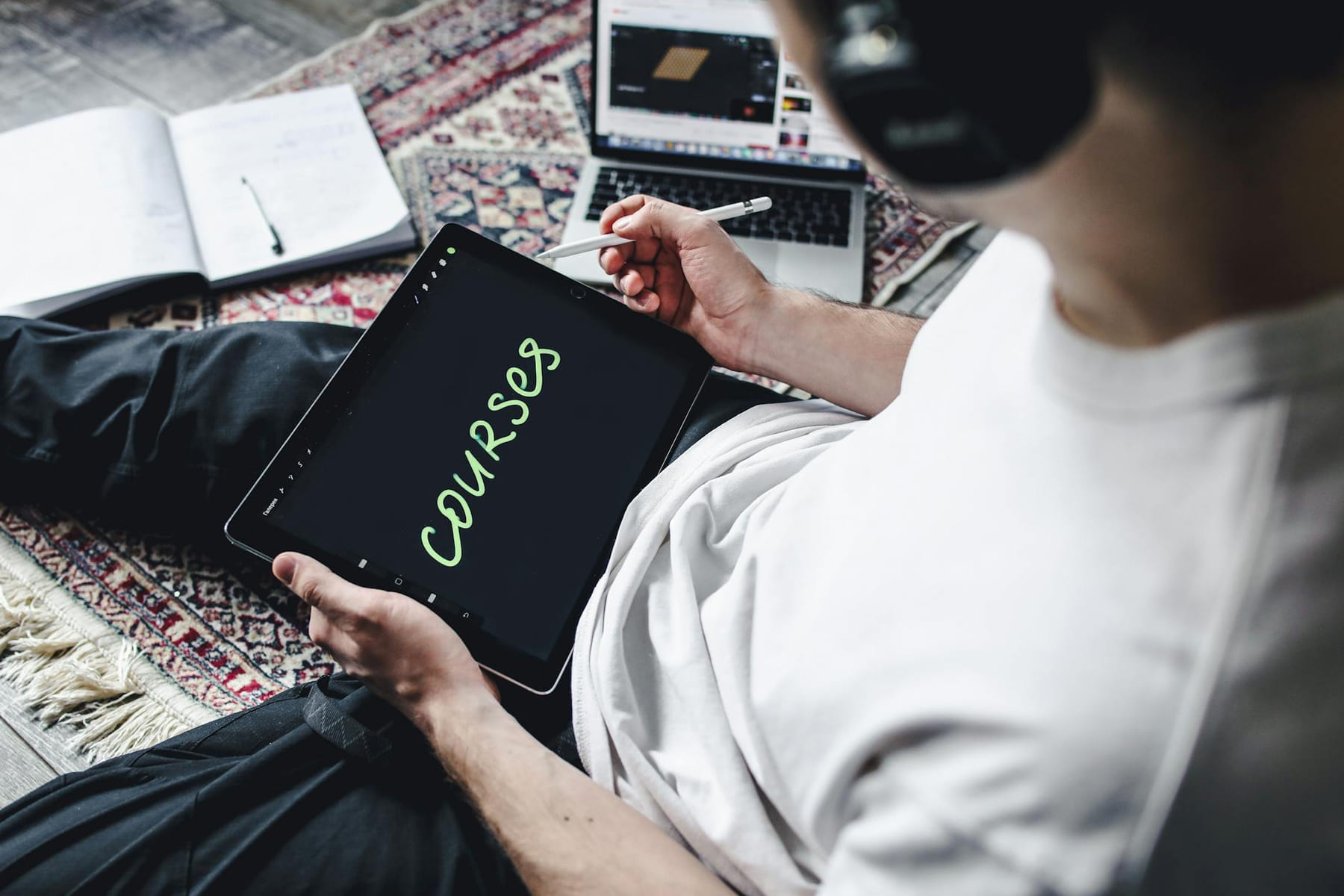 Person studying online courses using a digital tablet while relaxing indoors with headphones. on Skill Forge