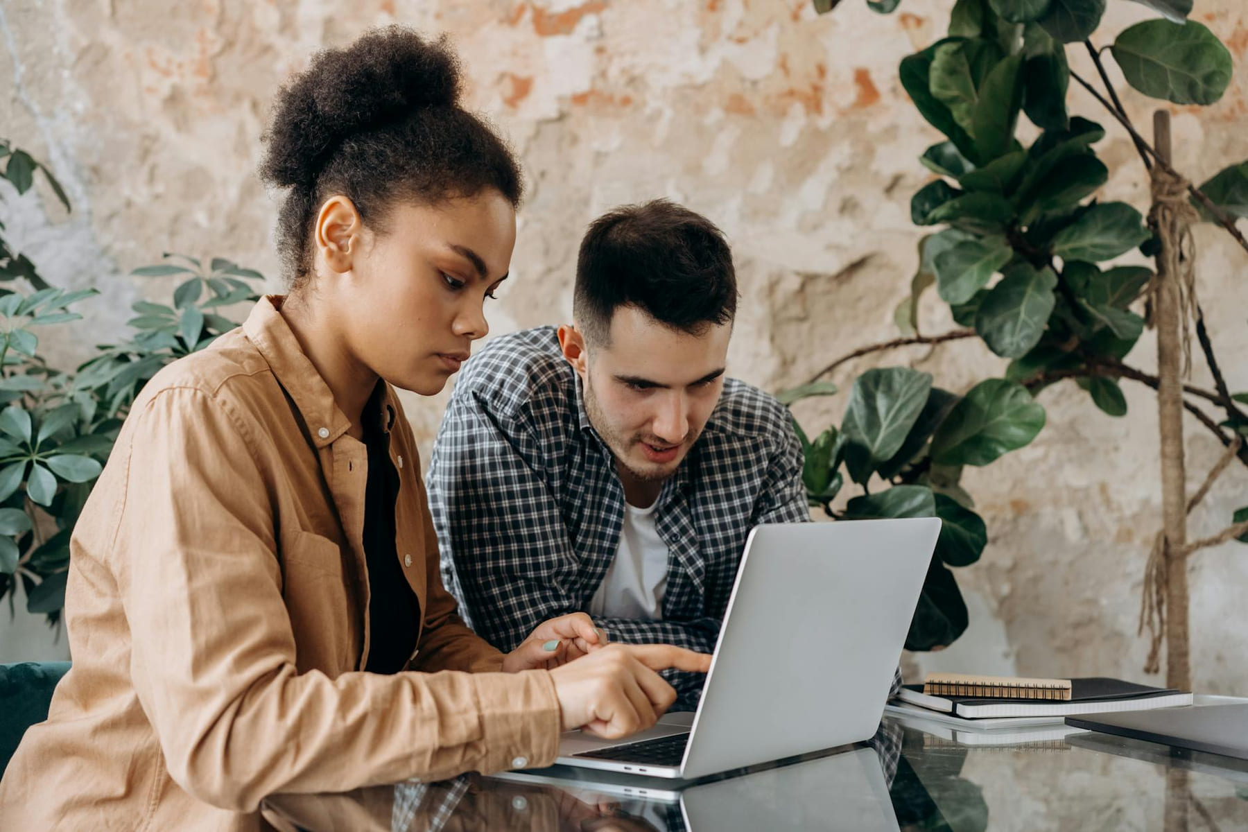 Two young adults collaborate on a project using a laptop in a modern workspace. on Skill Forge
