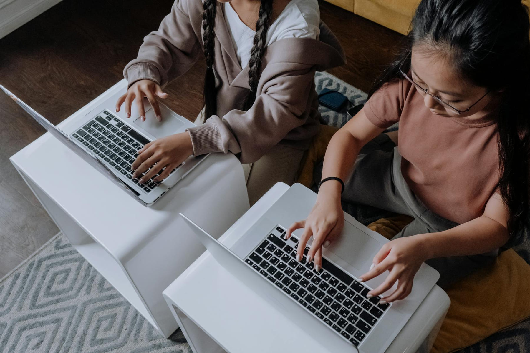 Two girls typing on laptops for learning and studying together indoors. on Skill Forge