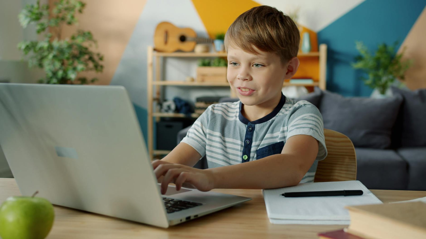 Young boy using a laptop for online learning at home with study materials nearby. on Skill Forge