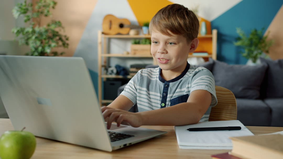 Young boy learning on a laptop at a desk. on Skill Forge