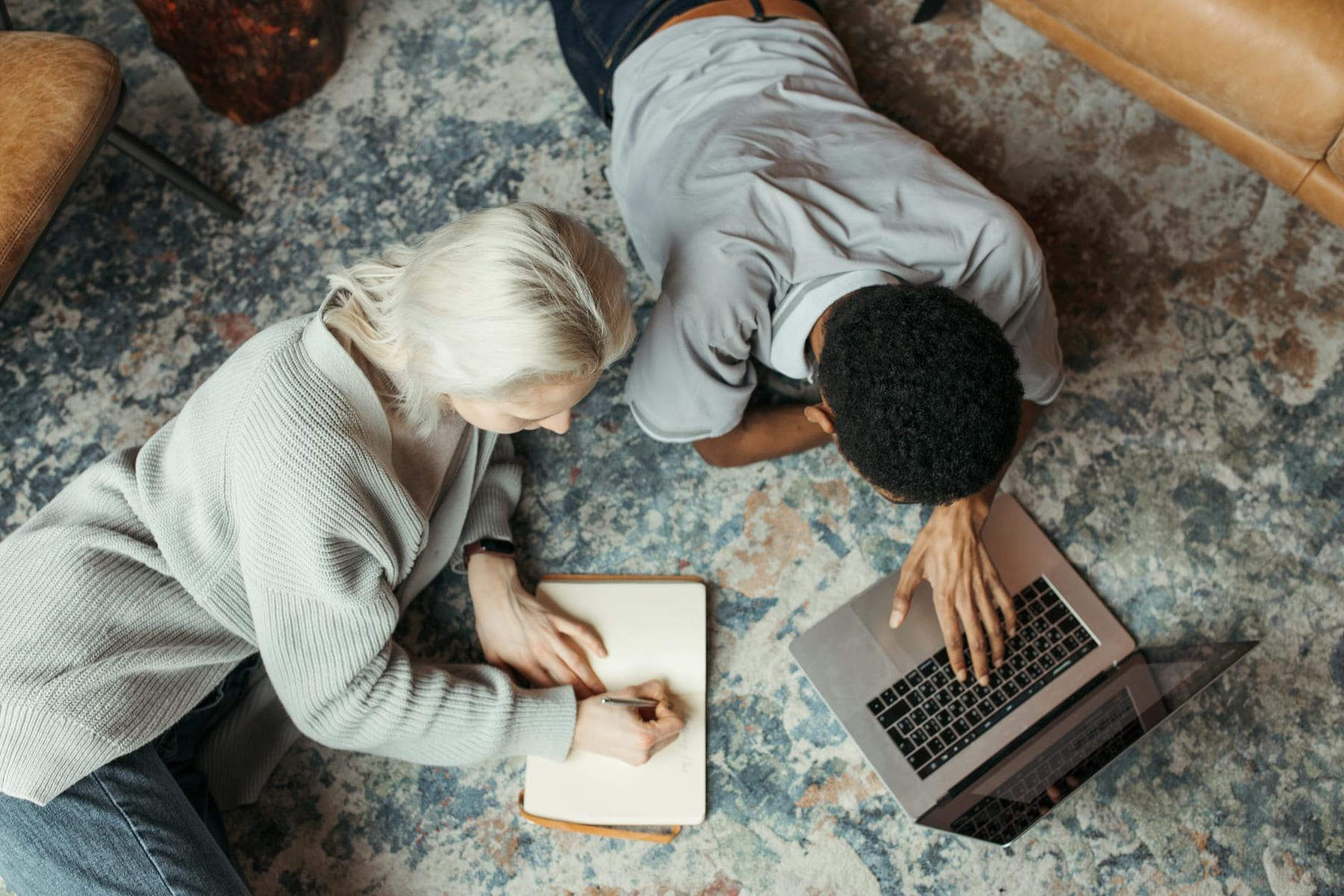 Two adults working together on the floor with a laptop and notebook. on Skill Forge