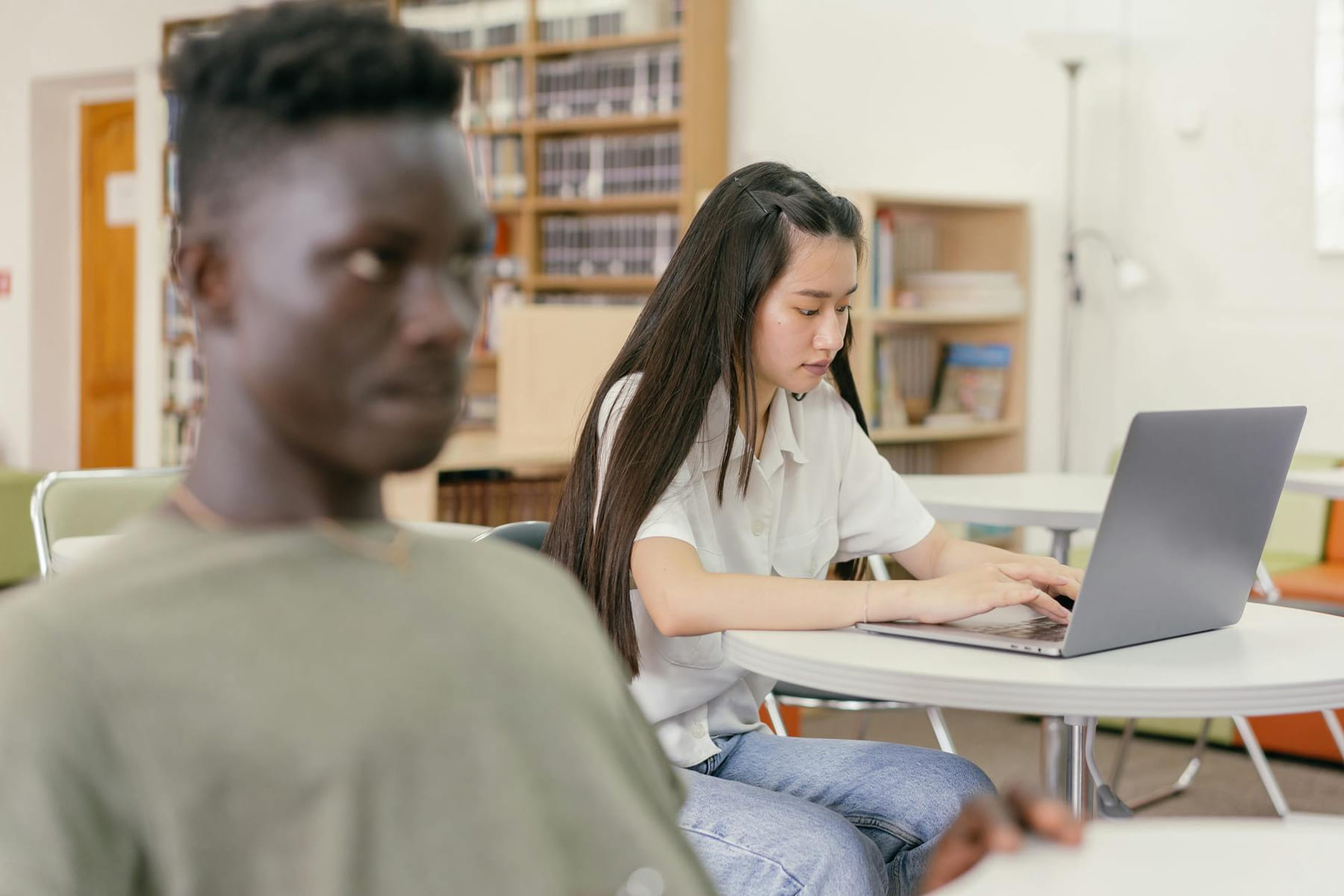 Two students focused on study in a contemporary library setting with laptops and books. on Skill Forge