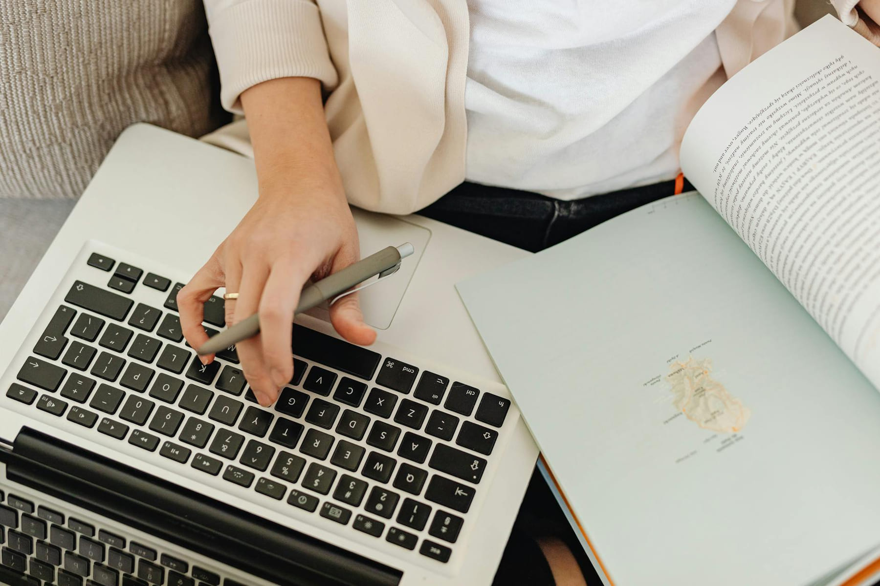 Close-up of a person working on a laptop and reading an open book. Ideal for educational themes. on Skill Forge
