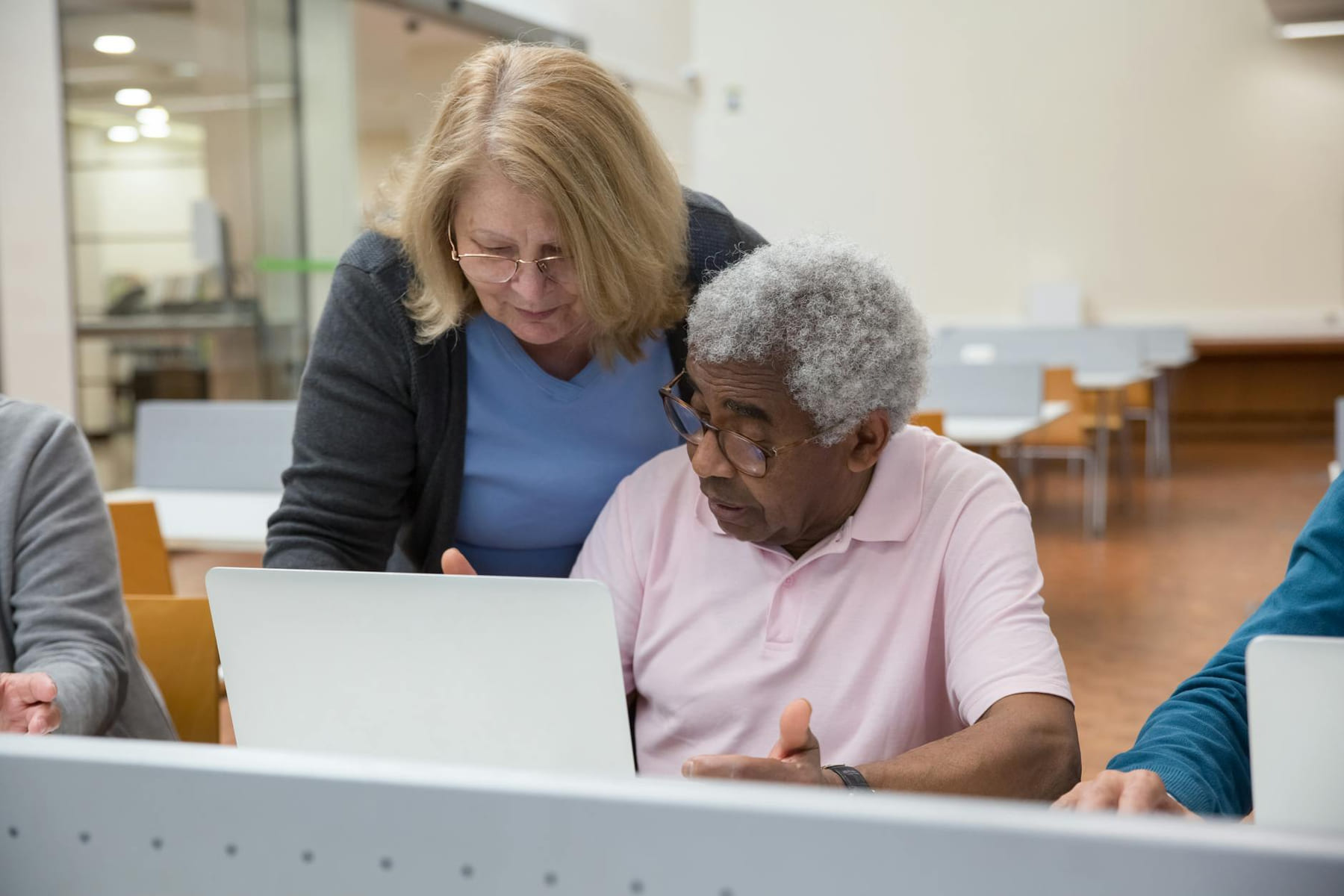 Elderly man and woman in classroom learning to use laptops, showcasing senior education and technology skills. on Skill Forge