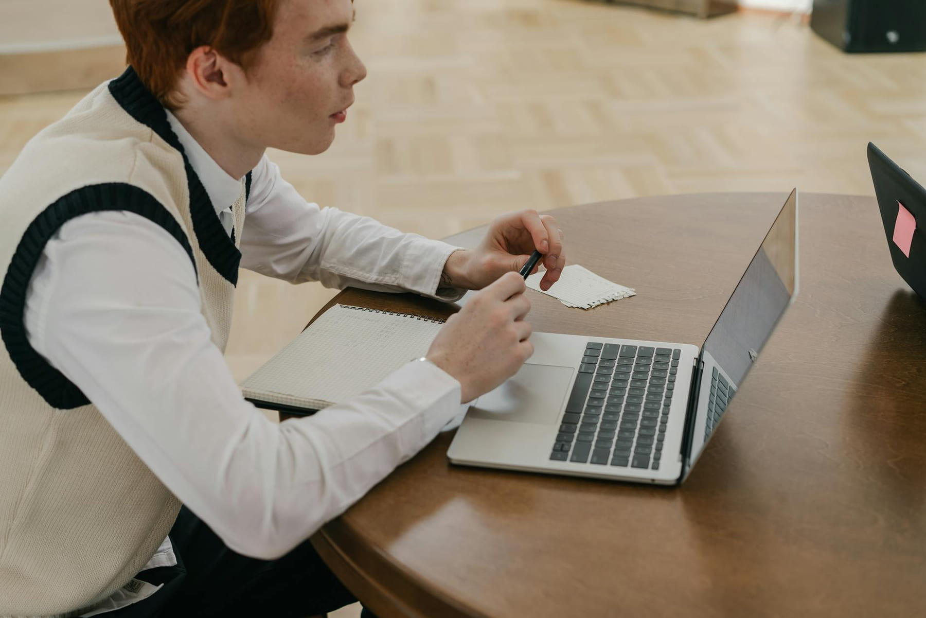 A young man engaged in online learning using a laptop and notebook indoors. on Skill Forge