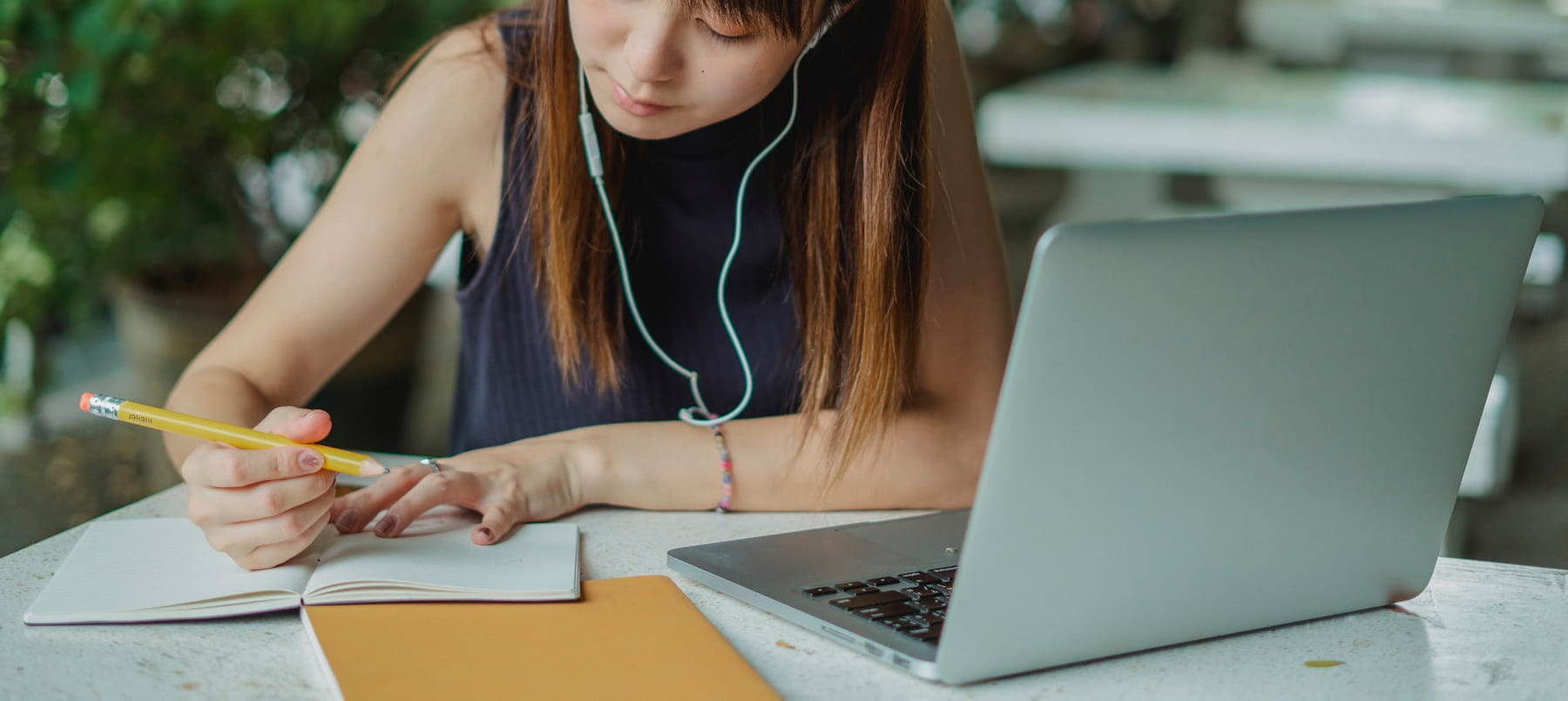 A young woman takes notes while studying with a laptop. Ideal for educational and lifestyle concepts. on Skill Forge